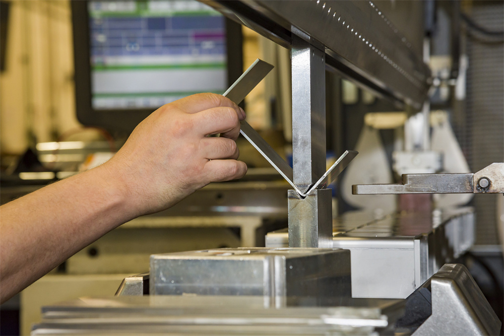 Worker operating a metal press brake in a modern workshop