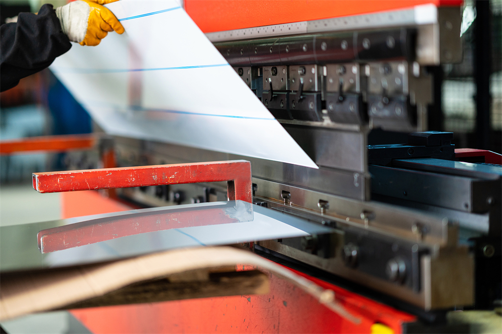 Worker operating a press brake in a metal fabrication factory