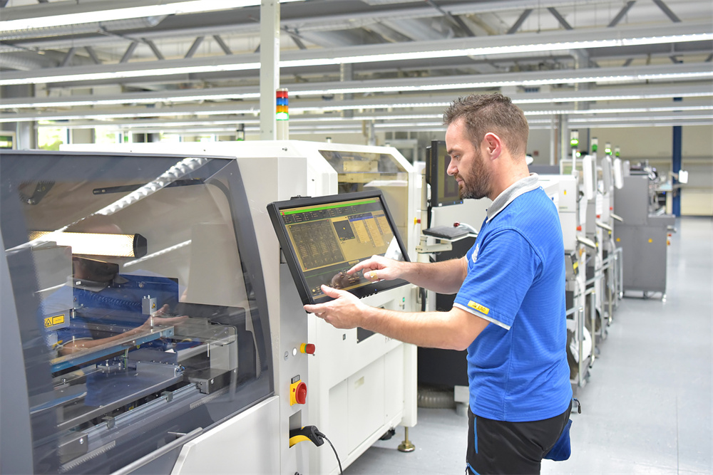 Technician inspecting electronic components and cooling systems in a factory
